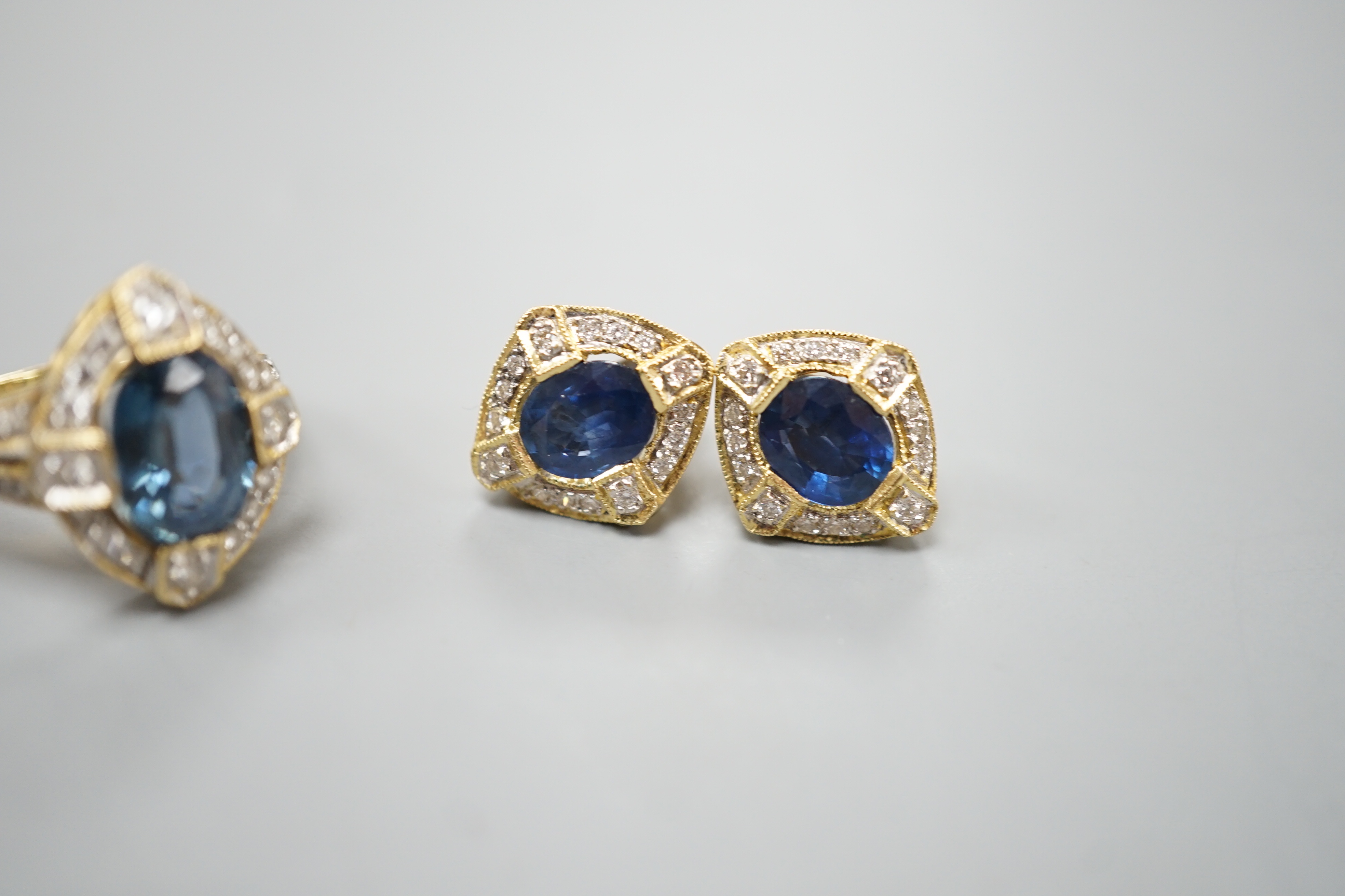 A modern suite of 18k, sapphire and diamond cluster set jewellery, comprising a dress ring, size L/M and pair of earrings, 14mm, gross weight 9.9 grams.